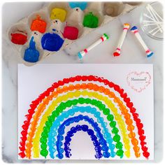 a rainbow made out of gummy bears next to some crayons and paint