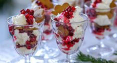 small desserts are arranged in glass dishes on a white tablecloth with pine branches