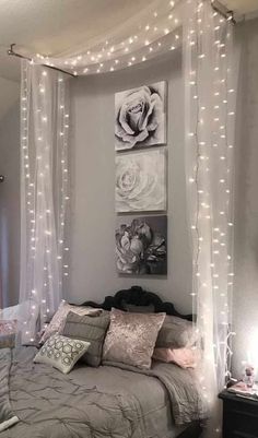 a bedroom with lights strung over the headboard and canopy bed, along with pictures on the wall