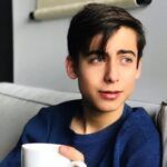 a young man sitting on a couch holding a coffee mug