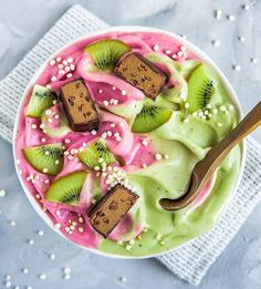 a bowl filled with kiwi and ice cream on top of a white table cloth