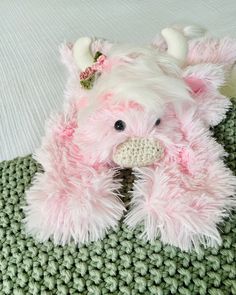 a pink stuffed animal laying on top of a green blanket