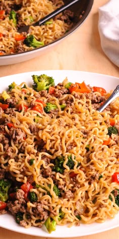 two plates filled with noodles, meat and vegetables