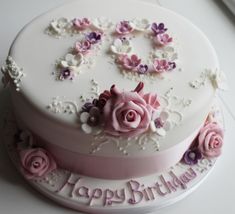 a birthday cake decorated with pink roses and white frosting