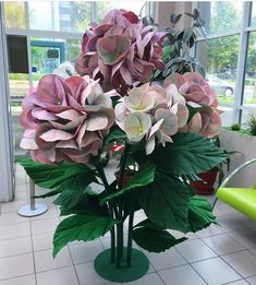 a vase filled with pink and white flowers on top of a tiled floor next to a green chair