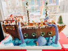 a cake made to look like a boat with dolphins on it and christmas decorations in the window