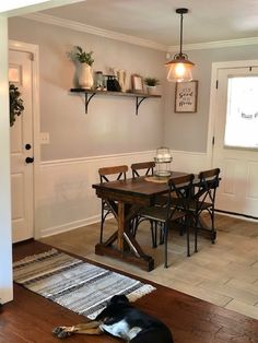 a dog laying on the floor in front of a dining room table