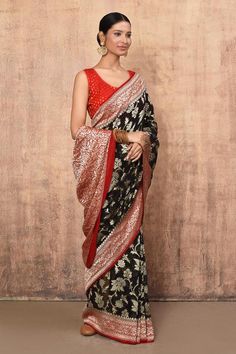 Black banarasi handloom cotton chiffon saree crafted with all over intricate gold zari floral jaal pattern and contrast red vine pattern border. Comes with running blouse piece.
Components: 1
Pattern: Handwoven
Type Of Work: Floral Pattern
Fabric: Handloom Cotton Silk
Color: Black
Other Details: 
Saree Length: 5.5 mtrs
Metallic border
Product Weight : 1 kg
Note: The stitched blouse worn by the model is not for sale
Occasion: Reception - Aza Fashions Black Bohemian Saree With Woven Motifs, Ceremonial Black Handloom Saree, Unstitched Black Handloom Pre-draped Saree, Black Handloom Silk Pre-draped Saree, Black Cotton Saree With Printed Border, Floral Pattern Fabric, Vine Pattern, Blouse For Women, Chiffon Saree