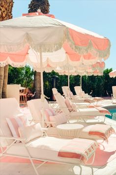 lounge chairs and umbrellas are lined up by the pool