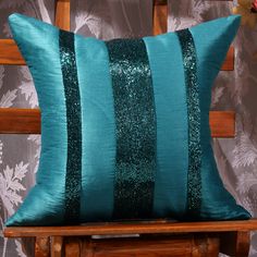 a teal pillow with sequins on it sitting on a wooden rocking chair