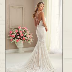 a woman in a wedding dress looking back at the camera with pink flowers behind her