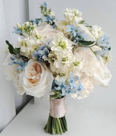 a bridal bouquet with blue and white flowers on a window sill in front of a door