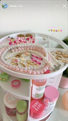 an assortment of jewelry is displayed on a white shelf with pink and green flowers in the background