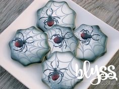 four cookies decorated with spider webs on a plate