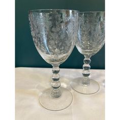 two clear goblets sitting on top of a white table covered in glass beads