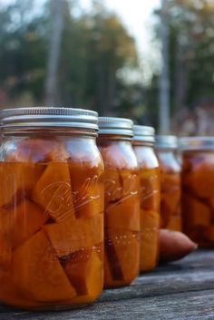 jars filled with pickles sitting on top of a wooden table