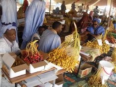 people are shopping at an outdoor market with bananas and other fruits on display in boxes