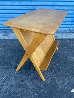 a wooden table sitting on top of a cement floor next to a blue wall and metal door