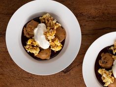 two white plates topped with desserts on top of a wooden table next to each other