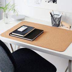 a white desk with a black chair and a book on it next to a potted plant