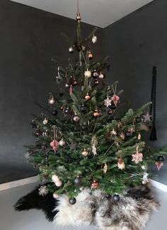 a small christmas tree with ornaments on it's top and a black cat underneath