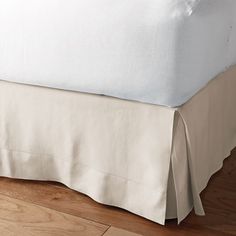 a bed with a white bedspread on top of it and a wooden floor