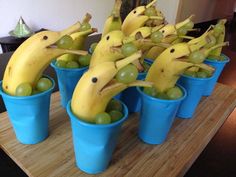 some bananas and grapes in blue cups on a table