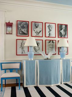 a living room with blue chairs and pictures on the wall above them, along with two lamps