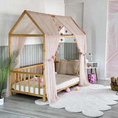 a child's bed with a canopy and pillows on the floor next to a potted plant