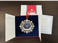 an open book with a medal in it on top of a table next to some cards