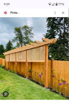 a wooden fence that is next to a green yard with flowers and plants on it