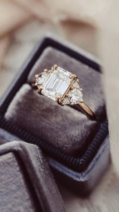 an engagement ring sitting on top of a velvet box