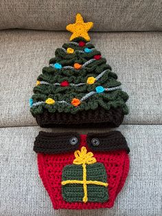 two crocheted christmas trees sitting on top of a couch next to each other