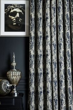 a black and white room with blue curtains, a silver vase and an art print on the wall