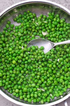 peas being cooked in a pot with a spoon