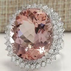 an oval shaped pink stone surrounded by white diamond halos in front of a beige background