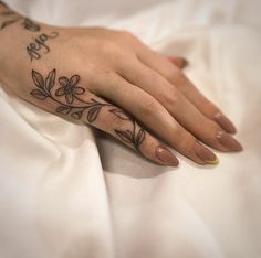 a woman's hand with a flower tattoo on it