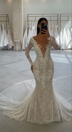 a woman in a wedding dress taking a selfie with her cell phone at the bridal gown shop