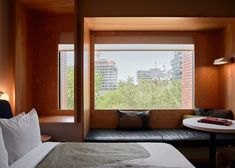 a bed sitting in a bedroom next to a window filled with lots of windows and pillows