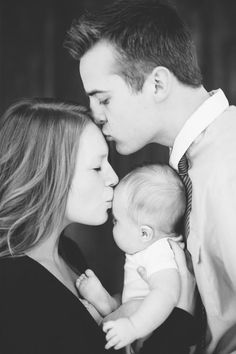 a black and white photo of a man, woman and baby with their noses to each other