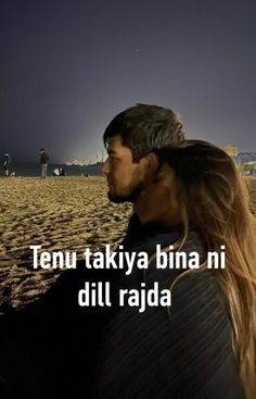 a man with long hair standing on top of a sandy beach next to the ocean