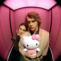 a man holding a hello kitty doll next to a woman in a star wars costume