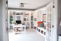 a home office with white bookcases and lots of books on the shelves in it