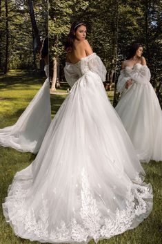 two women in wedding gowns standing on grass