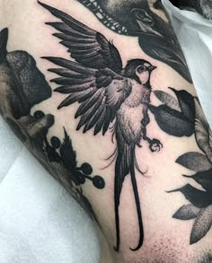 a black and white photo of a bird on someone's arm with flowers around it