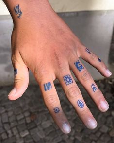 a person's hand with blue ink on it and two different symbols painted on their fingers