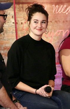 a woman sitting in front of a brick wall