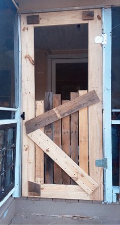 an open wooden door on the side of a building with wood planks in it