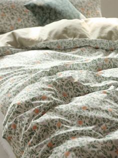 an unmade bed with floral sheets and pillows