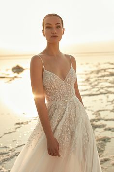 a woman in a wedding dress standing on the beach